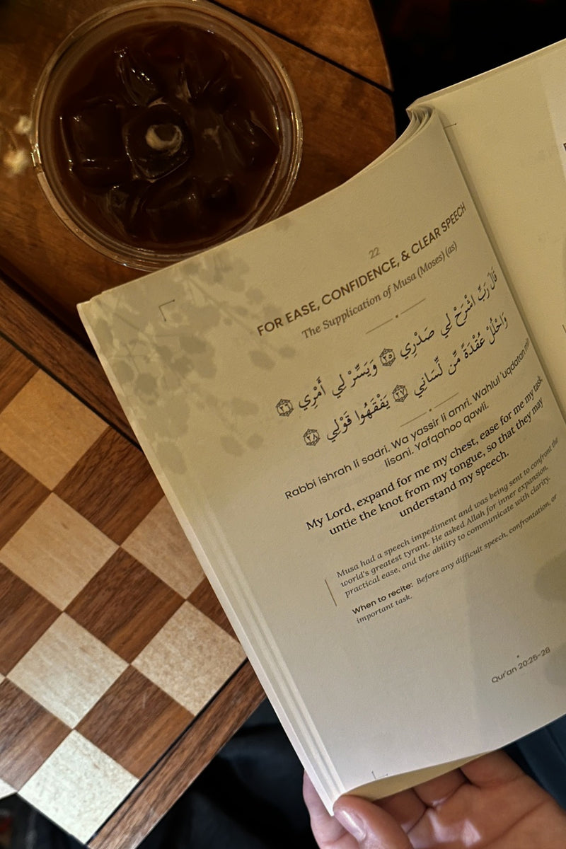 An open page of Dhikr beside a coffee, with Arabic, transliteration, and English